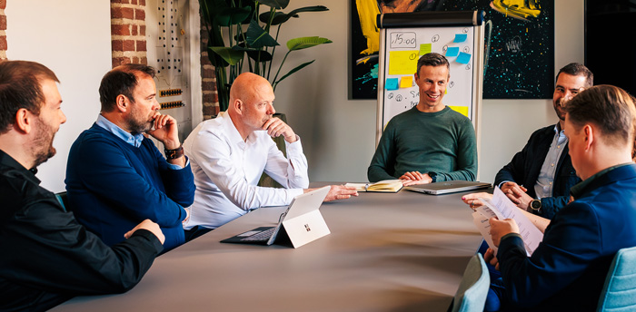 Groep met zakelijke klanten rondom grote tafel die training volgen